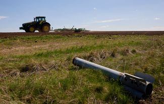 Трактор в поле под Высокопольем — работа происходит на фоне элемента корпуса ракеты, рухнувшего прямо на сельхозугодья